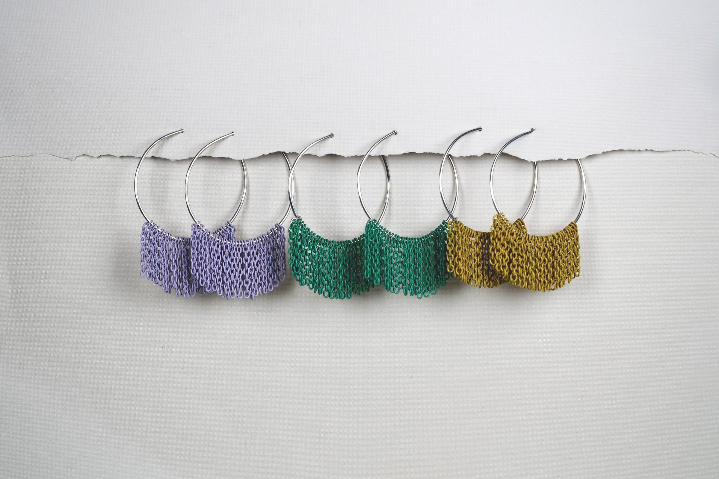 Leiah Hoop earrings with textured patterns in purple, green, and gold on a white background.