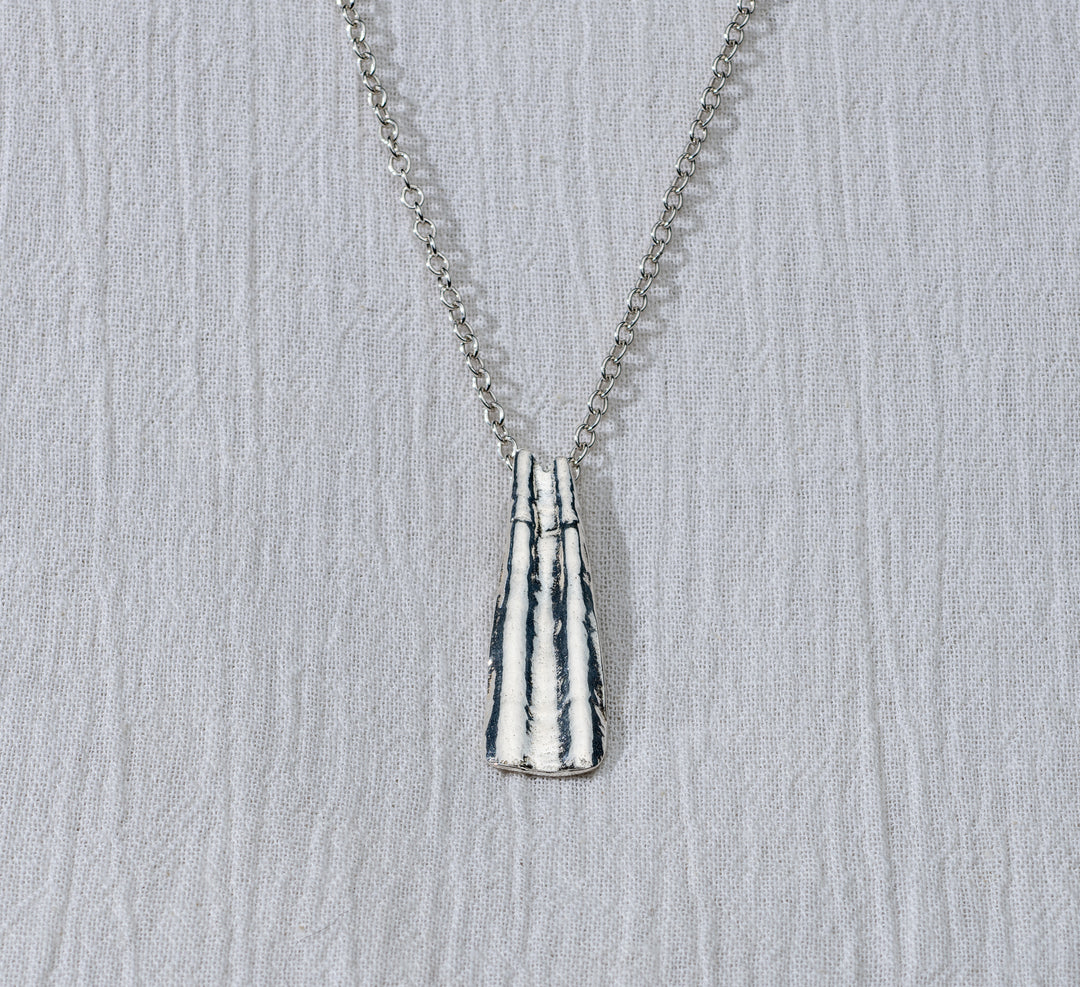 Silver necklace with a textured pendant on a light gray background