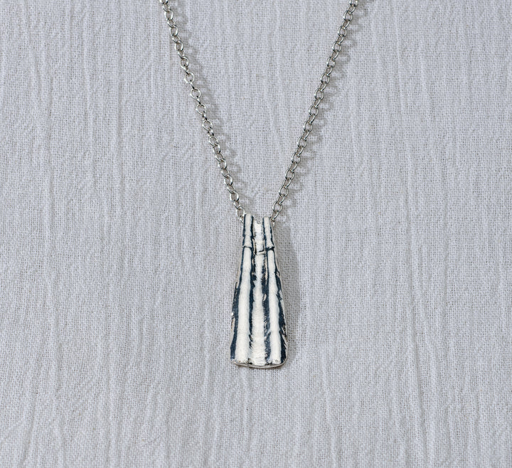 Silver necklace with a textured pendant on a light gray background