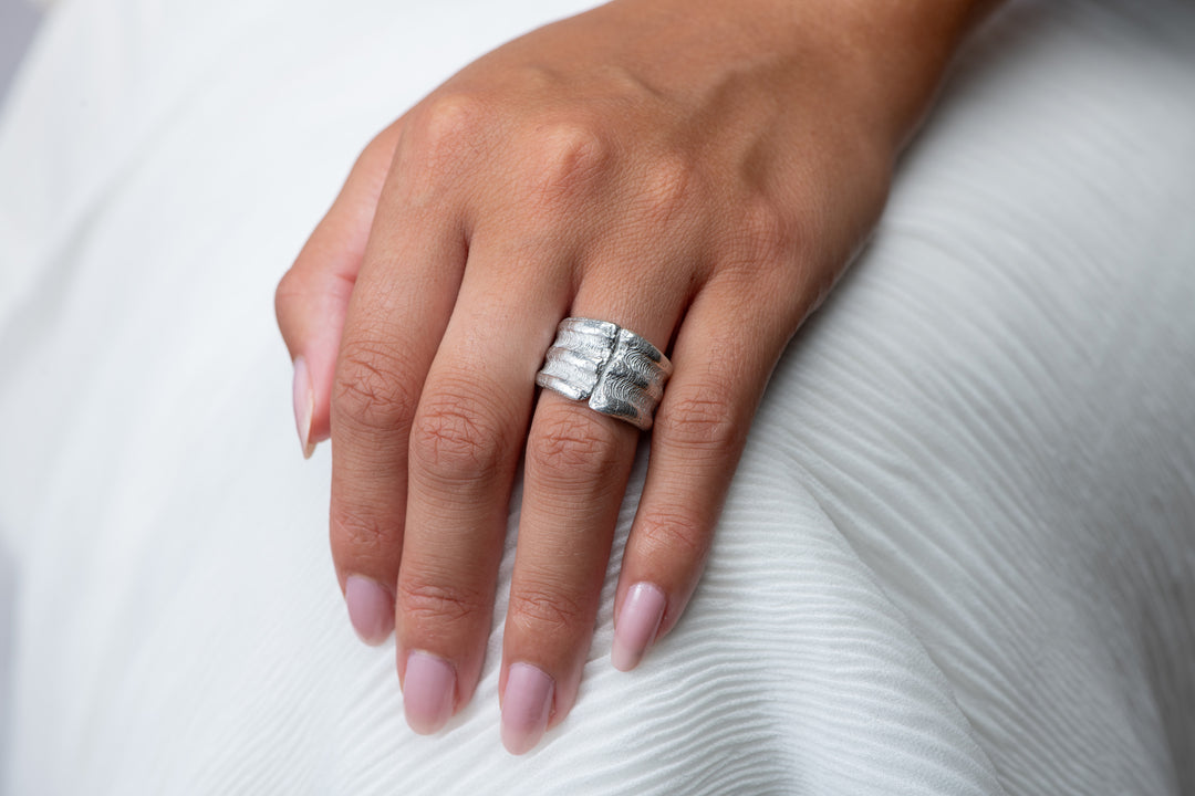 Hand wearing a silver ring on a white background