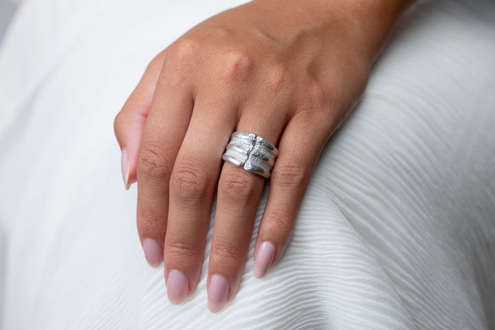 Hand wearing a silver ring on a white background